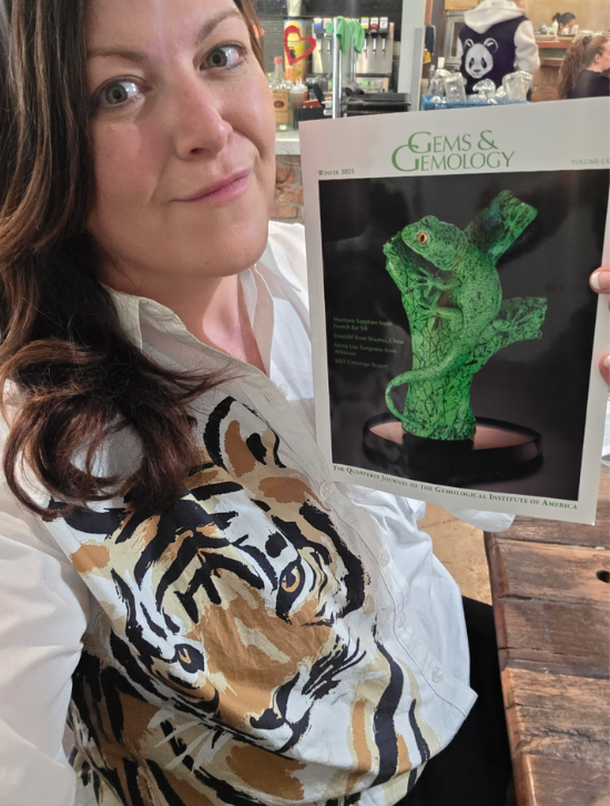 Crystel Thompson holding a copy of Gems and Geology containing an article on her findings 