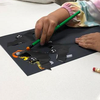 Child's hands making construction paper bat art